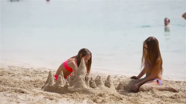 Két boldog kislány jól szórakozik a trópusi parton, együtt játszanak. — Stock videók