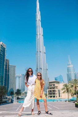 Arka planda gökdelenlerle Dubai 'de yürüyen mutlu bir aile..