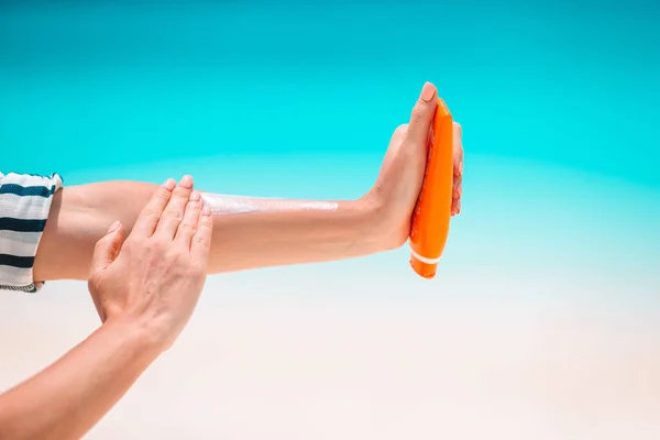 Bella giovane donna che tiene una crema solare sdraiata sulla spiaggia tropicale — Foto Stock