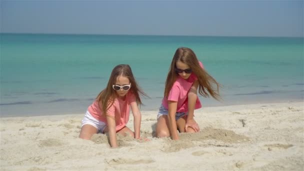 Дві маленькі щасливі дівчата весело проводять час на тропічному пляжі, граючи разом — стокове відео