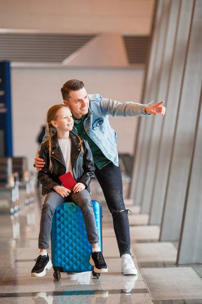 Familia feliz con equipaje y tarjeta de embarque en el aeropuerto esperando el embarque —  Fotos de Stock