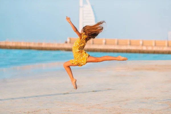 Schattig gelukkig klein meisje op wit strand bij zonsondergang. — Stockfoto