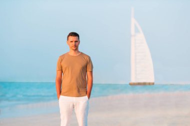 Genç adam sahilde eğleniyor.