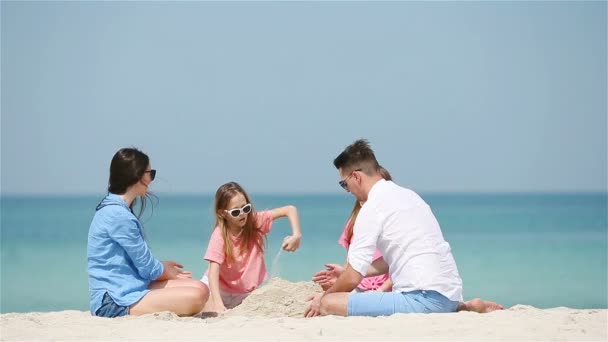 Rodina čtyř tvořících hrad z písku na tropické bílé pláži — Stock video