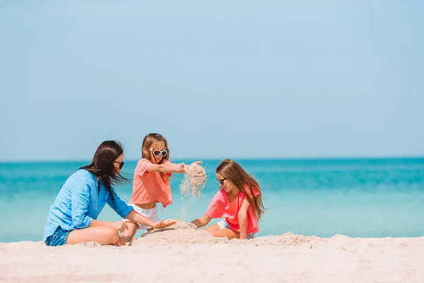Familia de cuatro haciendo castillo de arena en la playa tropical blanca —  Fotos de Stock