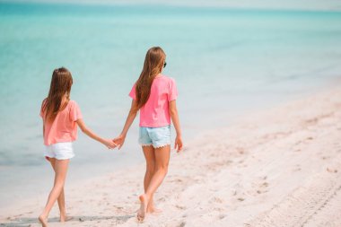 Küçük mutlu komik kızlar tropikal plajda birlikte oynarken çok eğlenirler..