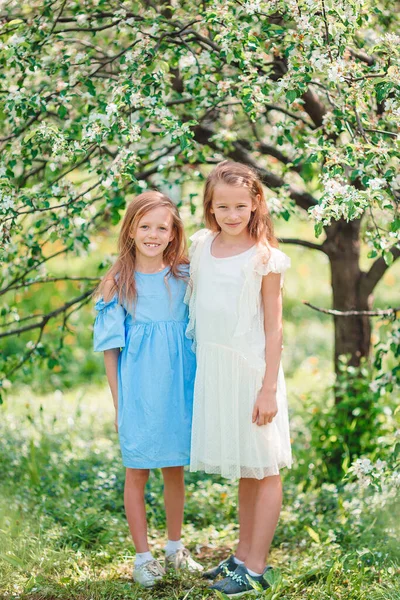 Adorables niñas en el jardín de manzanos en flor en el día de primavera —  Fotos de Stock