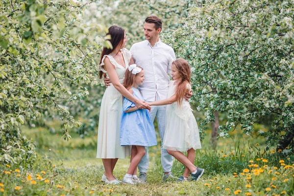 Adorable family in blooming cherry garden on beautiful spring day — Stock Photo, Image