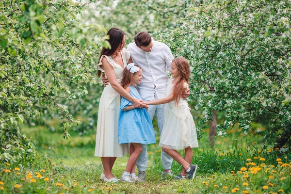 Urocza rodzina w kwitnącym wiśniowym ogrodzie w piękny wiosenny dzień — Zdjęcie stockowe