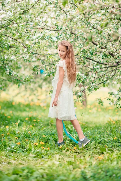 Rozkošná holčička v kvetoucí jablečné zahradě na krásném jarním dni — Stock fotografie