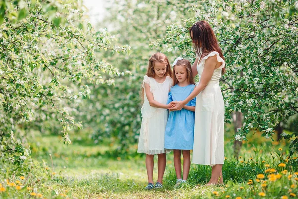 Meninas adoráveis com a jovem mãe em flor cereja jardim no belo dia de primavera — Fotografia de Stock