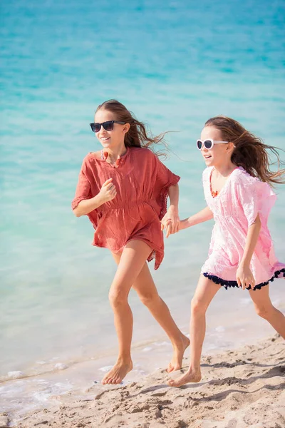 Lite glada roliga tjejer har mycket roligt på tropiska stranden leker tillsammans. — Stockfoto