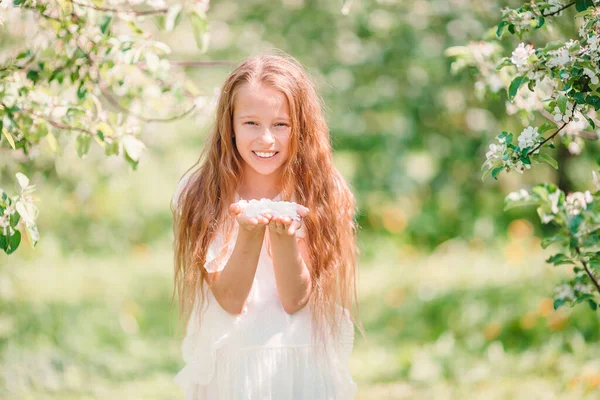 Liebenswertes kleines Mädchen im blühenden Apfelgarten an einem schönen Frühlingstag — Stockfoto