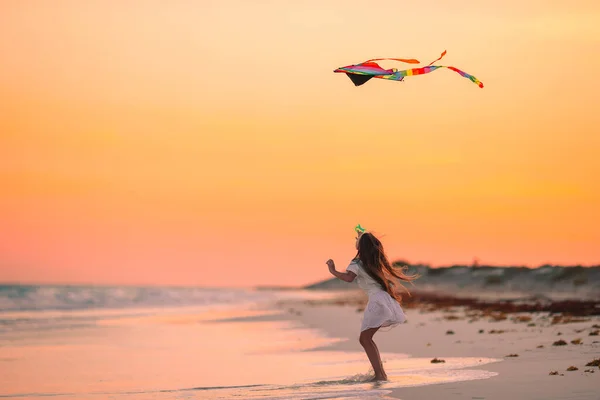 Klein meisje vliegen een vlieger op het strand met turquiose water — Stockfoto