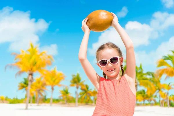 Lilla bedårande flicka med stora kokos på stranden — Stockfoto