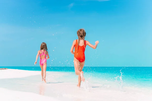 Pequeñas chicas divertidas felices tienen un montón de diversión en la playa tropical jugando juntos. — Foto de Stock