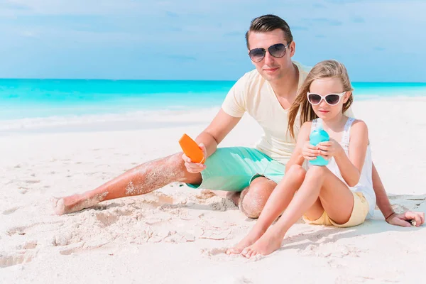 Giovane padre che applica la crema solare alla figlia — Foto Stock