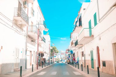 Adanın dar sokaklarında mavi balkonlar, merdivenler ve çiçekler.