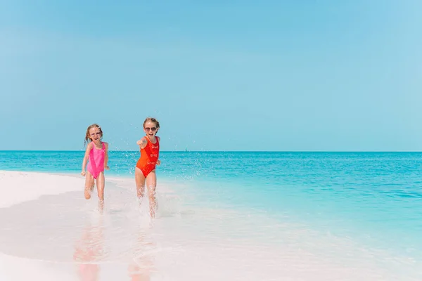 Pequeñas chicas divertidas felices tienen un montón de diversión en la playa tropical jugando juntos. —  Fotos de Stock