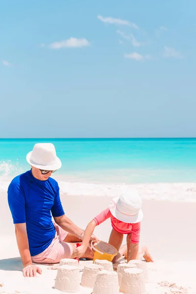 Baba ve çocuk tropik sahilde kumdan kale yapıyorlar. Aile plaj oyuncaklarıyla oynuyor. — Stok fotoğraf