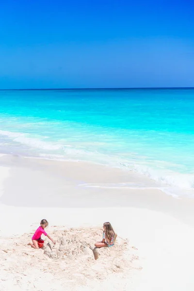 Zwei kleine glückliche Mädchen haben viel Spaß am tropischen Strand beim gemeinsamen Spielen — Stockfoto