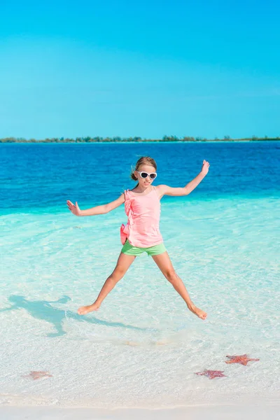 समुद्र तट पर सुंदर छोटी लड़की मज़ा कर रही है। मजेदार लड़की गर्मियों की छुट्टी का आनंद लें . — स्टॉक फ़ोटो, इमेज