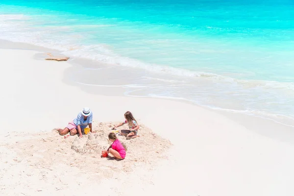 Father and little daughters making sand castle at tropical beach — Stock Photo, Image