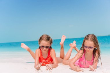 Küçük mutlu komik kızlar tropikal plajda birlikte oynarken çok eğlenirler..