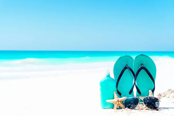 Suncream bottles, goggles, starfish and sunglasses on white sand beach background ocean — Stock Photo, Image