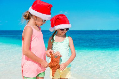 Beyaz boş sahilde deniz yıldızı ile sevimli küçük kızlar