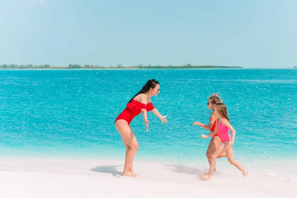 Tatlı küçük kızlar ve genç anne tropikal beyaz plajda — Stok fotoğraf