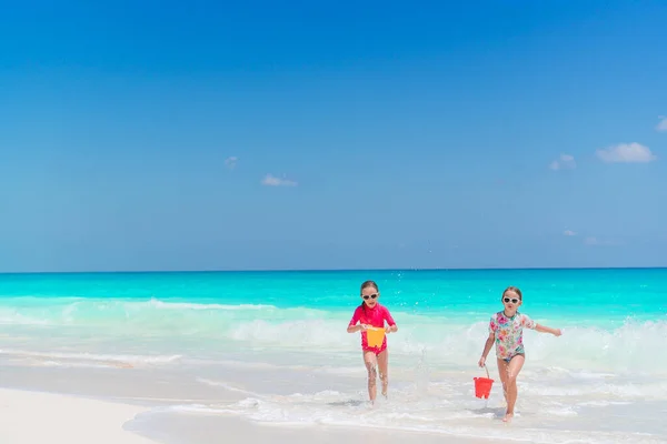 Två små glada flickor har mycket roligt på tropiska stranden leker tillsammans — Stockfoto