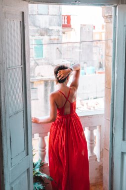 Havana 'daki eski balkonda kırmızı elbiseli çekici bir kadın.