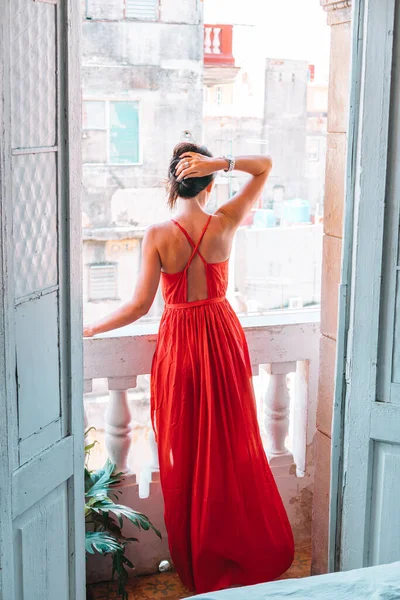 Mladá atraktivní žena v červených šatech na starém balkóně v bytě v Havaně — Stock fotografie