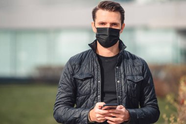 Modern bir binanın arka planında maske takan adam.,