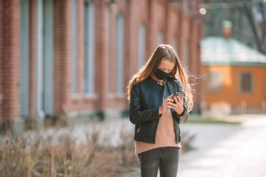 Modern bir binanın arka planında maske takan bir kız,
