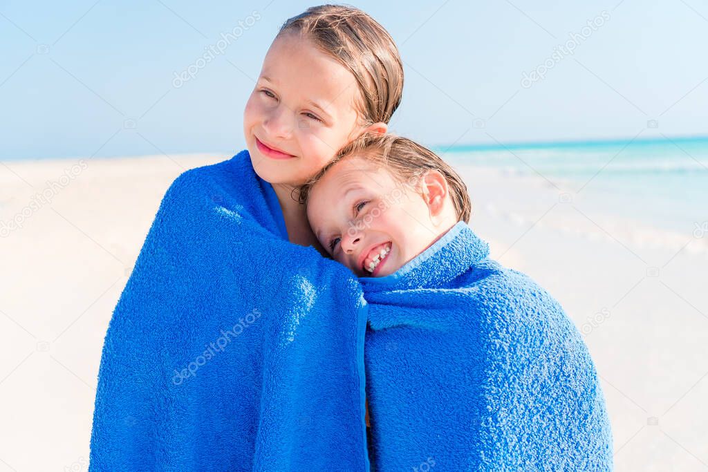 Little girls having fun running with towel and enjoying vacation on tropical beach with white sand and turquoise ocean water