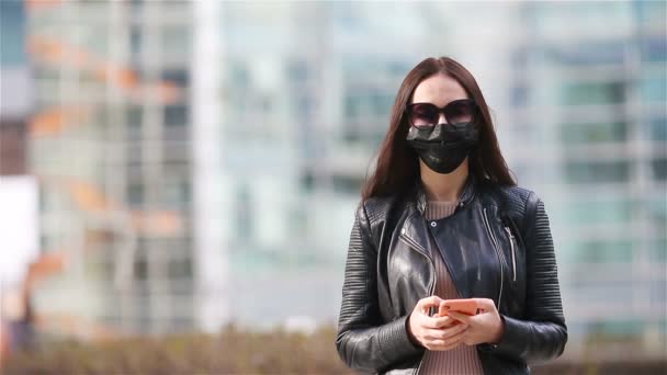Frau mit Maske vor dem Hintergrund eines modernen Gebäudes, — Stockvideo