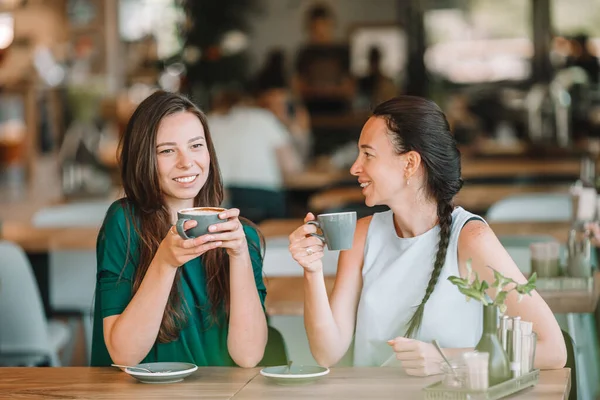 Szczęśliwy uśmiech młodych kobiet z filiżanek kawy w kawiarni. — Zdjęcie stockowe