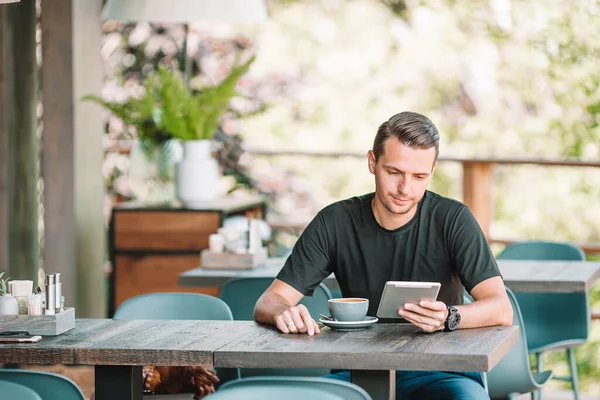 Jonge man met laptop in outdoor cafe het drinken van koffie. — Stockfoto