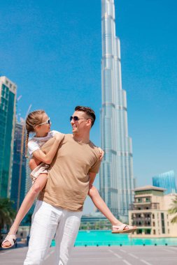 Arka planda gökdelenlerle Dubai 'de yürüyen mutlu bir aile..