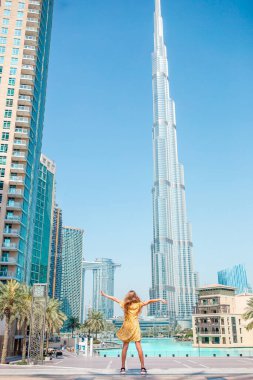 Arka planda gökdelenlerle Dubai 'de yürüyen mutlu kız..