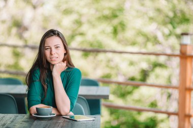 Güzel bir kadın açık kafede kahvaltı yapıyor. Mutlu genç şehir kadını kahve içiyor.