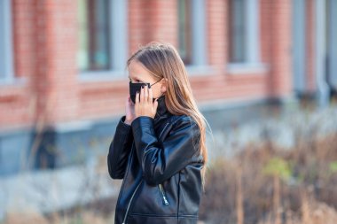 Modern bir binanın arka planında maske takan bir kız,