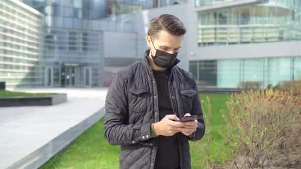 Homem usando uma máscara em um fundo de um edifício moderno, — Vídeo de Stock