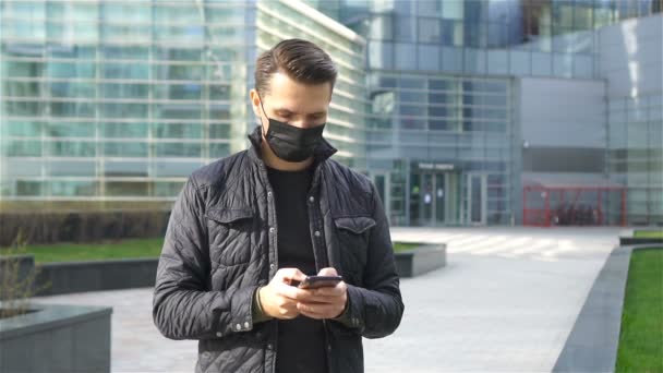 Hombre usando una máscara sobre un fondo de un edificio moderno, — Vídeos de Stock