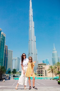 Arka planda gökdelenlerle Dubai 'de yürüyen mutlu bir aile..
