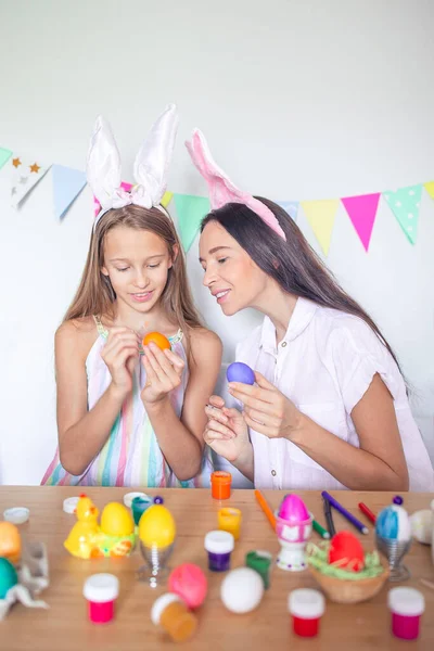 Mutter und ihre kleine Tochter bemalen Eier. Glückliche Familie bereitet sich auf Ostern vor. — Stockfoto