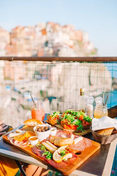 Fresh bruschettes, cheeses and meat on the board in outdoor cafe with amazing view in Manarola — Stock Photo, Image