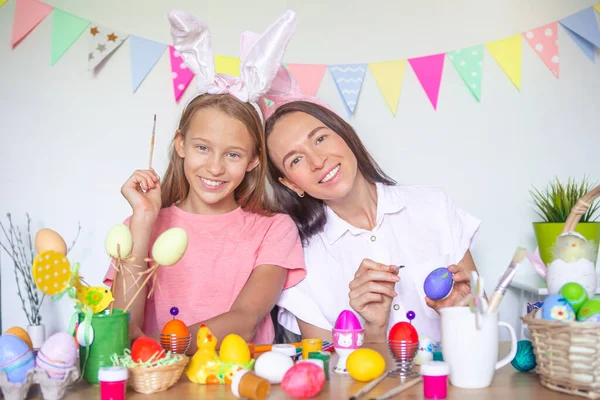 Matka i jej córeczka malują jajka. Szczęśliwa rodzina przygotowuje się do Wielkanocy. — Zdjęcie stockowe